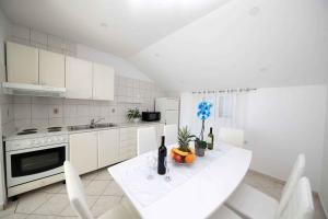 a white kitchen with a table with a bowl of fruit at Apartment Crikvenica 1 in Crikvenica