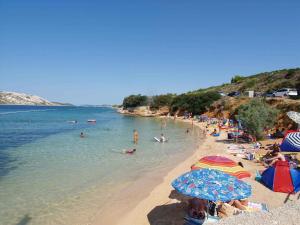 a beach with a bunch of people in the water at Apartments in Rab/Insel Rab 16117 in Mundanije