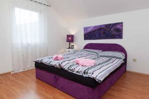 sypialnia z fioletowym łóżkiem z 2 różowymi ręcznikami w obiekcie Three-Bedroom Apartment in Crikvenica IV w mieście Klanfari