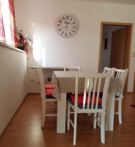 une table à manger et des chaises avec une horloge sur le mur dans l'établissement Apartment in Lopar with Two-Bedrooms 1, à Lopar