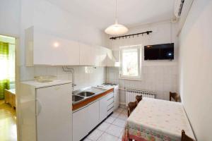 eine Küche mit weißen Schränken, einem Tisch, einem Tisch und einem Tisch in der Unterkunft Apartment in Pula with Two-Bedrooms 3 in Pula