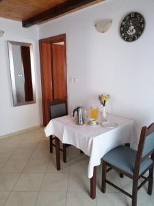 een witte tafel met stoelen en een klok aan de muur bij One-Bedroom Apartment in Baric Draga II in Barić Draga