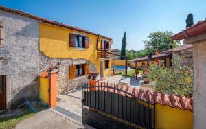 żółty dom z kotem siedzącym na płocie w obiekcie Holiday home Mali Vareski/Istrien 8734 w mieście Mali Vareški