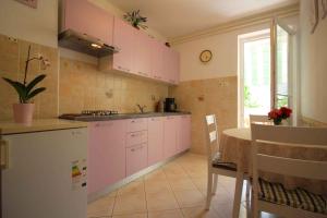 a kitchen with pink cabinets and a table with chairs at Apartments in Porec/Istrien 9899 in Poreč