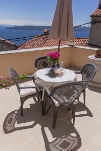 a table with two chairs and a umbrella on a balcony at Holiday home in Moscenice 15209 in Mošćenice