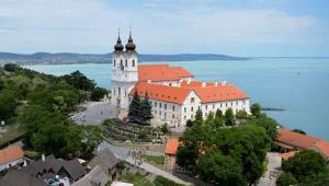 ein großes weißes Gebäude mit einem Uhrturm vor dem Wasser in der Unterkunft Holiday home in Tihany - Balaton 20236 in Tihany + 35 Fotos