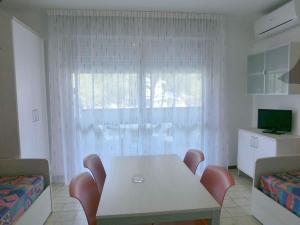ビビオーネにあるApartment in Bibione Iのテーブルと椅子、窓が備わる客室です。