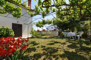 a garden with a table and chairs and flowers at One-Bedroom Apartment in Stinjan I in Štinjan