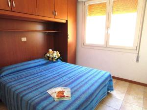 a bedroom with a blue bed with a book on it at Apartment in Bibione 24583 in Bibione