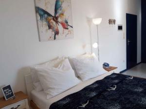 a bedroom with a bed with white pillows and a butterfly painting at Vodice Apartment 2 in Vodice