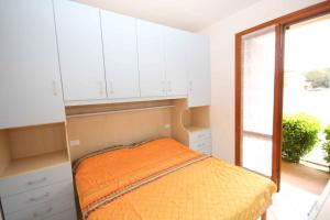 1 dormitorio con cama, armarios blancos y ventana en Apartments in Rosolina Mare 24858, en Rosapineta