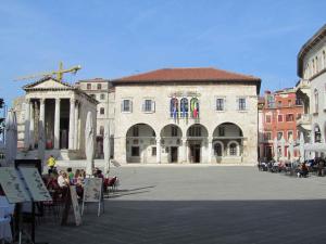 a large building with people sitting at tables in a courtyard at One-Bedroom Apartment in Pula IX in Veruda