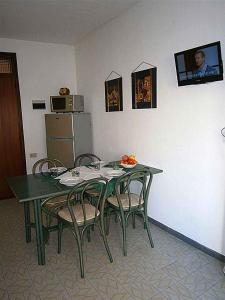 ビビオーネにあるApartments in Bibione 24393の緑豊かなダイニングテーブル(椅子付)、冷蔵庫が備わります。