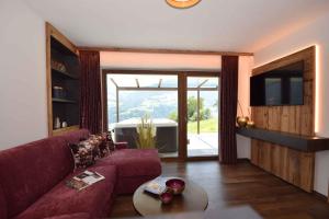 カルテンバッハにあるHoliday home in Kaltenbach/Zillertal 876のリビングルーム(赤いソファ、ガラスの引き戸付)
