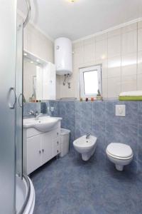 a white bathroom with a toilet and a sink at Apartment Slatine 6 in Trogir