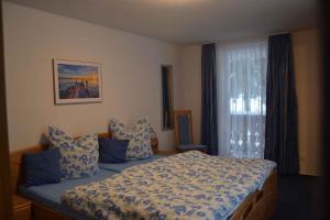 Schlafzimmer mit einem Bett mit blauer Bettwäsche und einem Fenster in der Unterkunft Apartment Todtmoos 4 in Vordertodtmoos
