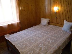 ein Bett in einem Holzzimmer mit einer Decke darauf in der Unterkunft Holiday home in Balatonmariafürdo 19400 in Balatonmáriafürdő