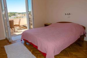 a bedroom with a bed with a view of a balcony at Apartment Banjol 23 in Rab