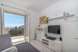 a living room with a television and a balcony at Apartment Okrug Gornji, Ciovo 2 in Trogir
