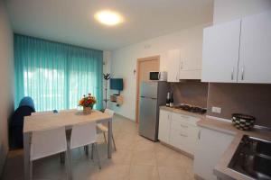 una cocina con armarios blancos y una mesa. en Apartment in Rosolina Mare 15, en Rosolina Mare