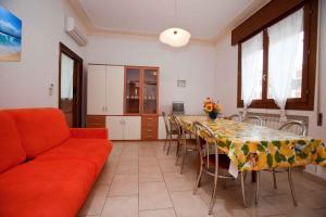 ロゾリーナ・マーレにあるApartment in Rosolina Mare 3のリビングルーム(テーブル、赤いソファ付)