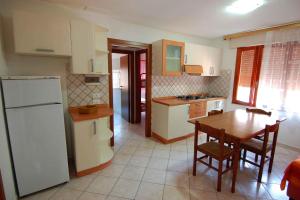 羅莎皮內塔的住宿－Apartments in Rosolina Mare 24864，厨房配有桌子和白色冰箱。