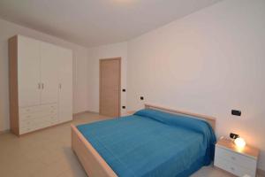 ロザピネタにあるTwo-Bedroom Apartment Rosolina Mare near Sea 9の白いベッドルーム(青いベッド1台、キャビネット付)