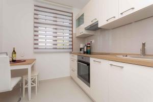 a kitchen with white cabinets and a table and a sink at Apartment in Silo/Insel Krk 13438 in Šilo