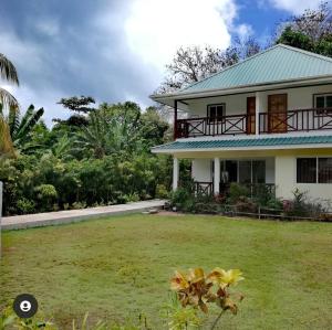 a white house with a green roof and a yard at Lucy's guesthouse in La Digue