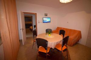 a dining room with a table with chairs and a television at Apartment Kampor 4 in Kampor