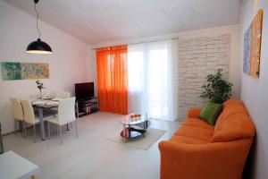 a living room with an orange couch and a table at Apartment Banjole 1 in Banjole
