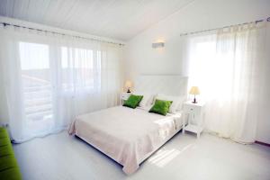 a white bedroom with a bed with green pillows at Apartment Banjole 1 in Banjole