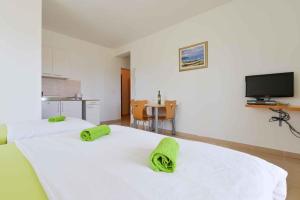 um quarto com 2 camas brancas com toalhas verdes em Apartment Ljubac 5 em Ljubac