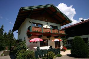 a house with a balcony and an umbrella at Holiday home Strobl/Salzburger Land 103 in Weissenbach