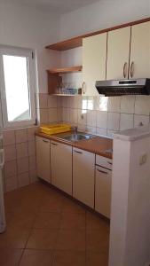 a kitchen with white cabinets and a sink and a window at Apartment Lopar, Primorje-Gorski Kotar 4 in Lopar