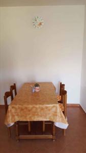 a dining room table with chairs and a clock on the wall at Apartment Lopar, Primorje-Gorski Kotar 4 in Lopar