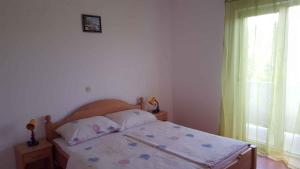 a bedroom with a bed and a window at Apartment Lopar, Primorje-Gorski Kotar 4 in Lopar