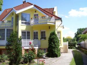 a yellow house with white balconies and bushes at Apartment Siofok, Lake Balaton 1 in Siófok