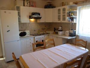 eine Küche mit einem Tisch und einem weißen Kühlschrank in der Unterkunft Holiday home Balatonalmadi/Balaton 17971 in Balatonalmádi