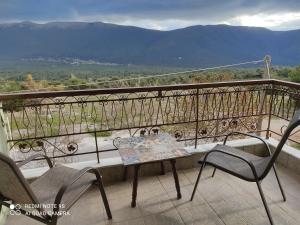 a table and chairs on a balcony with a view at Xenonas ΚITHΑIRON in Vília