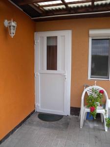 a white door of a house with a chair and a window at Holiday home in Balatonfenyves 18379 in Balatonfenyves