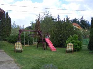 a playground with two chairs and a slide in a yard at Holiday home Cserszegtomaj - Balaton 18288 in Cserszegtomaj