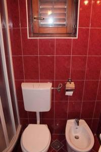 a red tiled bathroom with a toilet and a sink at Apartment Valbandon, Istria 12 in Štinjan