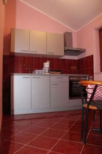 a kitchen with white cabinets and a red tile floor at Apartment Valbandon, Istria 12 in Štinjan