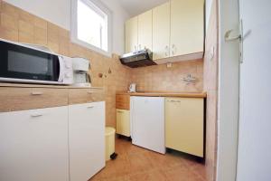 a small kitchen with white cabinets and a microwave at Apartment Vrsi -Mulo 2 in Kod Mula