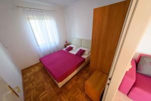 ein kleines Schlafzimmer mit einem rosa Bett und einem Fenster in der Unterkunft Apartment Kozino 1O in Kožino