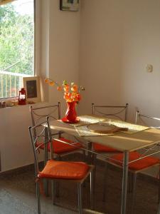 einen Esstisch mit Stühlen und eine Vase mit Blumen in der Unterkunft Apartment Zlarin 1 in Zlarin