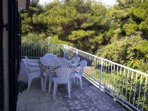 einen Tisch und Stühle auf einem Balkon mit Bäumen in der Unterkunft Apartment in Supetar/Insel Brac 5905 in Supetar