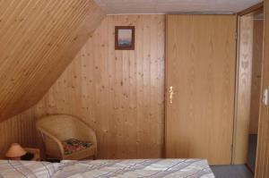 una camera da letto con pareti in legno, un letto e una sedia di Apartment Neuendorf - Hiddensee 2 a Neuendorf
