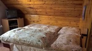 Holiday home in Pernink/Erzgebirge 1672 في Pernink: سرير في غرفة بجدار خشبي